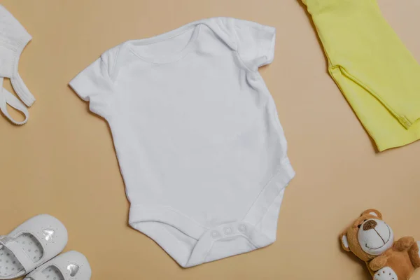 Vit Baby Bodysuit Beige Bakgrund Med Baby Skor Nalle Gula — Stockfoto