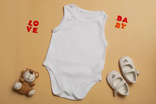 ベビー服モックアップテンプレート新生児のための空白の白いジャンプスーツ 靴やベージュの背景にテディベア テキスト トップビューのためのスペース — ストック写真