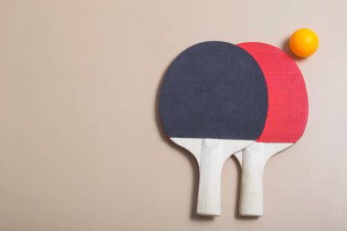 Bej arka planda iki tenis raketi ve turuncu ve beyaz toplar. Spor eğlencesi. Ping pong raketleri. Pankart