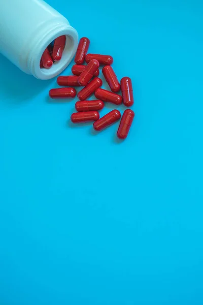 Medical concept tube with pills, capsules of red color on a blue background. Medicines prtiv kovid19 or vitamins for immunity. Recovery after covid 19. Dietary supplement.