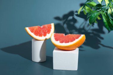 Greyfurt dilimleri, kürsüde sert gölgeli taze greyfurt. Gri ve mavi arka planda en az gıda yaratıcı kavram. Citrus hala yaşıyor..