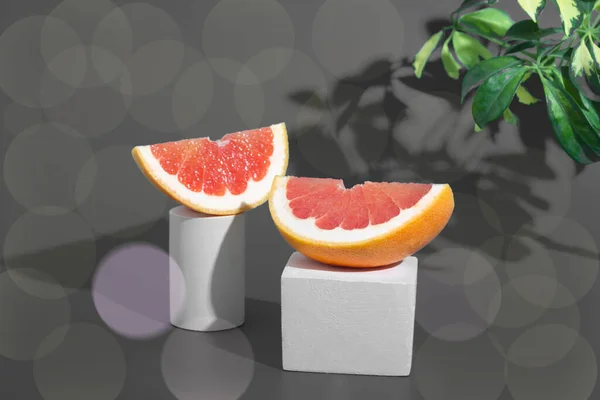 Greyfurt dilimleri, kürsüde sert gölgeli taze greyfurt. Koyu gri arka planda çok az yiyecek yaratıcı konsept. Citrus hala yaşıyor..
