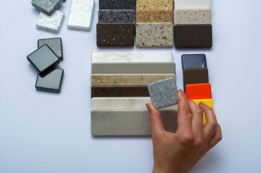 Doğal taşlardan, üst görüntüden, yakın plan. Bir kadının eli tamir malzemelerinin reklamını yapar. Döşemeler, fayanslar, tezgahlar..