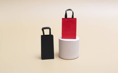 Siyah Cuma konsepti, renkli arka planda beyaz podyumda siyah ve kırmızı alışveriş torbalarının maketi. Kara Cuma. Kopyalama alanı ile