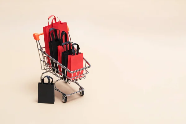 Concept Black Friday, maquette de sacs à provisions en papier noir et rouge avec chariot sur fond coloré. Vente Black Friday. — Photo