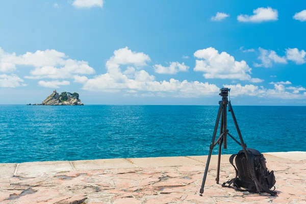 Bir tripod ve deniz arka plan üzerinde bir sırt çantası