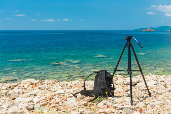 Bir tripod ve deniz arka plan üzerinde bir sırt çantası