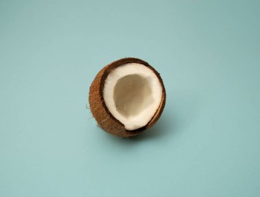 Hindistan cevizinin yarısı minimum düzeyde. Mavi arka planda olgun hindistan cevizleri. Uzayı kopyala Pop sanat tasarımı, yaratıcı yaz konsepti. Pankart. Organik yiyecekler.