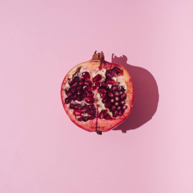 Pembe arka planda kırmızı nar meyvesi. Minimum düz konsept. Feminist sanat. Kadın doğası.