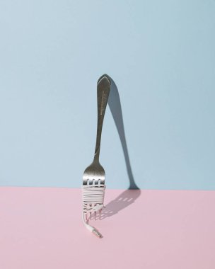 Parlak mavi ve pembe arka planı olan parlak bir çatal. Ev partisinde kalmak için yaratıcı bir kavram.