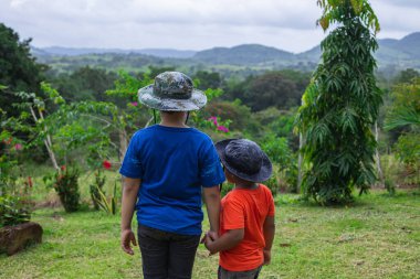 Çocuklar el ele tutuşarak tarlada yürüyor.