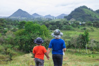 Çocuklar el ele tutuşarak tarlada yürüyor.