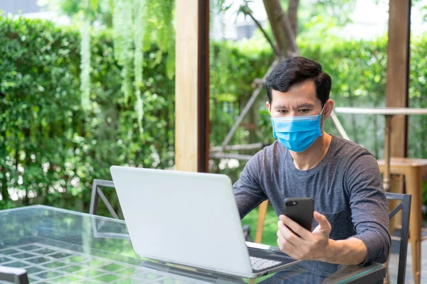 Ung Man Medicinsk Ansiktsmask Med Hjälp Smarttelefon Sms Medan Arbetar Stockfoto