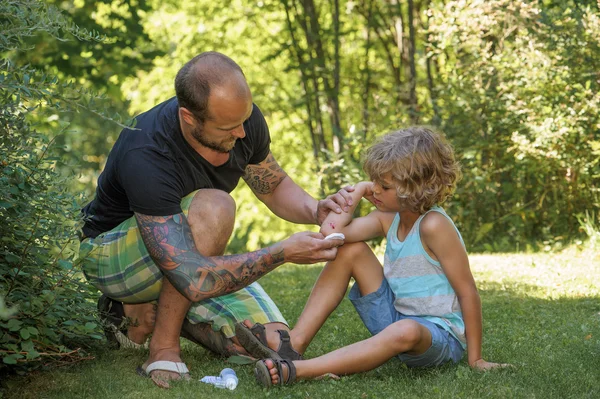 Dad puts antiseptic on sons elbow Stock Picture