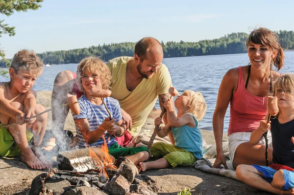 Family grilling sausages at campfire Stock Photo
