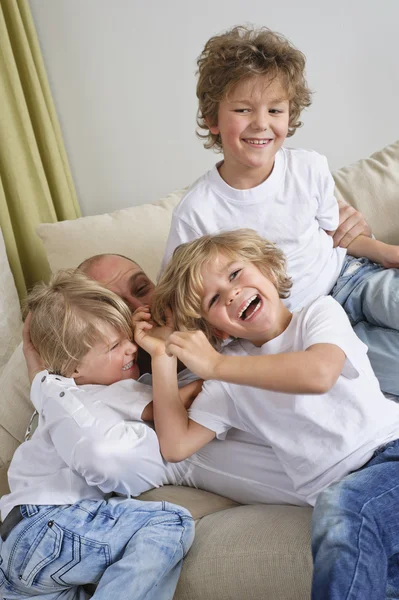 Niños saltando sobre papá —  Fotos de Stock