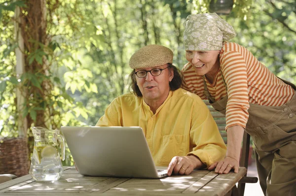 Senior couple outdoors with a laptop