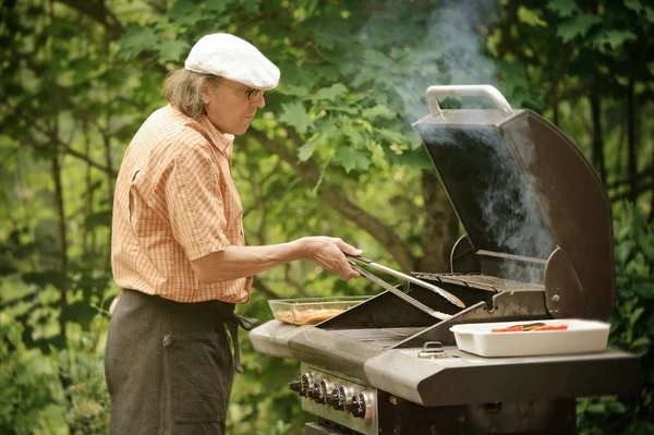 Senior man grilling outdoors — Stock Photo, Image