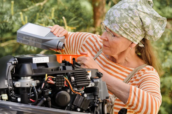 Senior woman changing engine oil Stock Photo