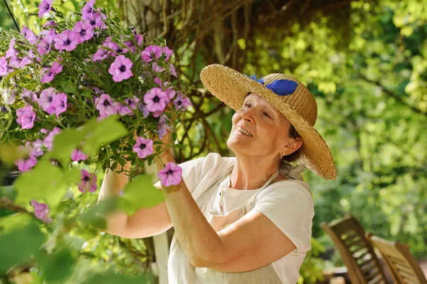 Senior woman tends flowers — Stock Photo, Image