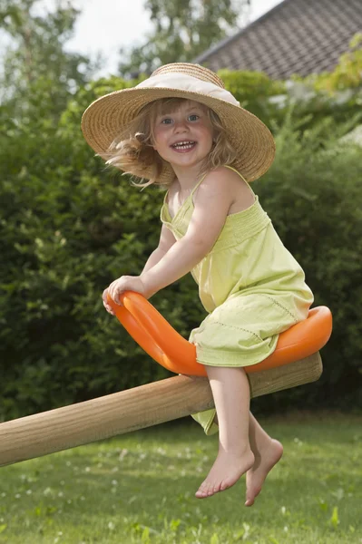 Child with hat on seesaw — Stock Photo, Image