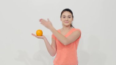 Bir portakal ve elma tutan kız