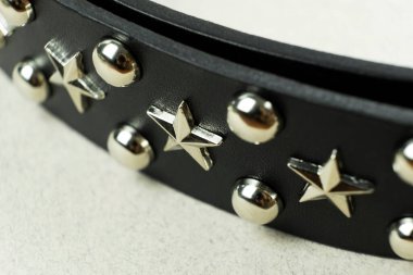 Gümüş yıldızlı siyah deri kemer ve bulanık gri arka planda oyuklar.