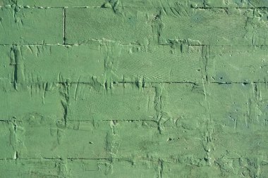 Büyük tuğlalardan oluşan eski püskü yeşil bir duvar. kabaca yüzey dokusu