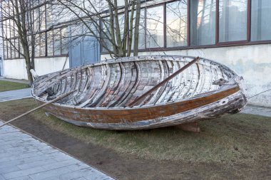Hangarın yanındaki çayırda eski, büyük, hırpalanmış ahşap bir tekne.