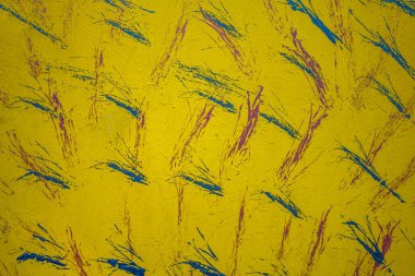 Mavi ve mor boya lekeli parlak sarı bir duvar. kabaca yüzey dokusu