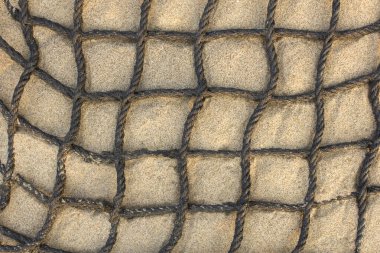 Aydınlık kumda siyah kareli halat ağı. Yaklaş. Doğal yüzey dokusu