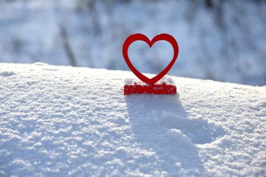 Kırmızı şamdanların yakın çekim şekli beyaz parlak masa üzerindeki kalplerin üzerinde gün ışığında bulanık arka planda. 