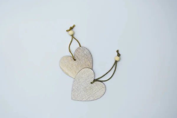 Küçük, açık bej, tahta kolyelerin üst görüntüsü kalp şeklinde beyaz arka plandaki lambalar ışığında. 
