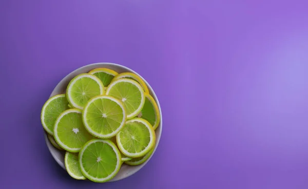 Gündüz vakti menekşe arkaplanda küçük parlak kireç dilimlerinin yukarıdan görünüşü