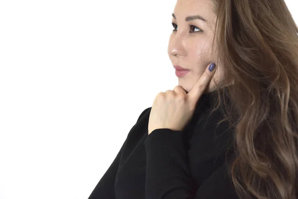 Ciddi, koyu kahverengi saçlı, yanağına parmağını koyan ve izole edilmiş beyaz arka plana dikkatlice bakan Asyalı genç bir kadının yan görüntüsü.