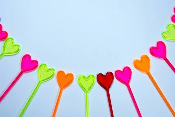 Yukarıdan, beyaz arka planda kalbi olan birçok küçük renkli kokkuyruk karışıklığı geliyor. 