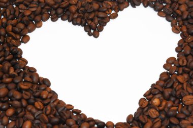 Beyaz kalp çerçevesinin yukarısından bir sürü koyu kahverengi kahve çekirdeği oluşmuş.