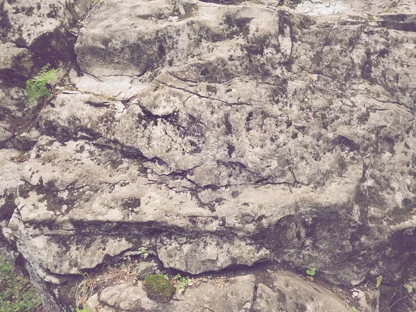 Antik karanlık dağ bloğunun arka planı çizgilerle ve otlarla kaplı yosunlarla kaplı.