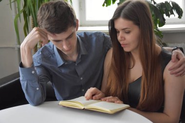 Yakışıklı koca ve güzel eş kitap okurken gündüzleri parlak, rahat bir dairede kanepede dinleniyorlar. 