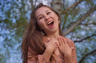 Güzel genç Asyalı kadın gülüyor ve parkta kameraya bakıyor. 