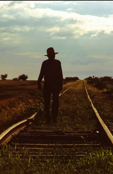 Küba 'da tren yolunda yürüyen şapkalı yaşlı bir adam.