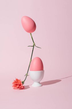 2021 Paskalya yaratıcı natürmort yaşam kompozisyonu. Pastel pembe yumurta bahar çiçeğinin üstünde dengeleniyor. Moda en düşük konsept.