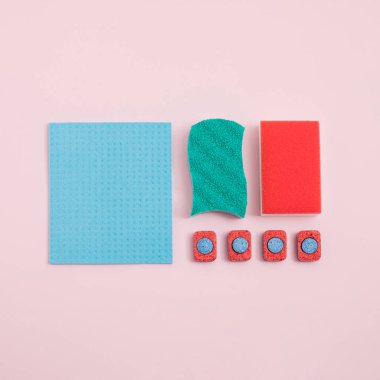 Bulaşık makinası tabletleri, renkli süngerler ve pastel arka grond üzerine mavi bez ile oluşturulan minimum bahar temizleme düzenlemesi. Yaratıcı, modaya uygun düz yatak.