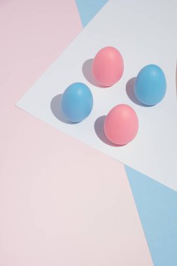 Pastel arka planda dört pembe ve mavi yumurtalı modern Paskalya kompozisyonu, fotokopi alanı ile. Dikey biçim.