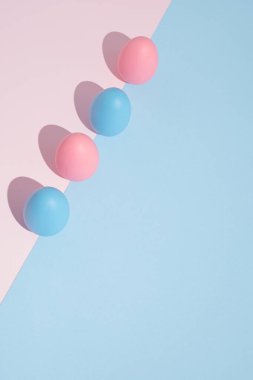 Pastel arka planda pembe ve mavi yumurtalarla modern Paskalya kompozisyonu..