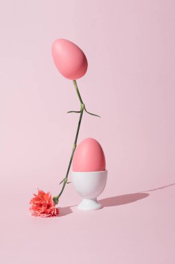 2021 Paskalya yaratıcı natürmort yaşam kompozisyonu. Pastel pembe yumurta bahar çiçeğinin üstünde dengeleniyor. Moda en düşük konsept.