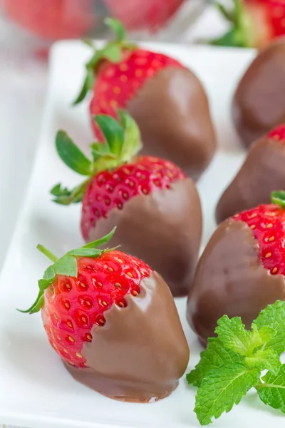 Strawberries covered with milk chocolate on a white plate — Stock Photo, Image