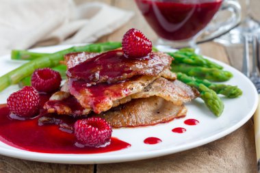 Domuz pirzola frambuaz sos ve beyaz plaka üzerinde kuşkonmaz ile