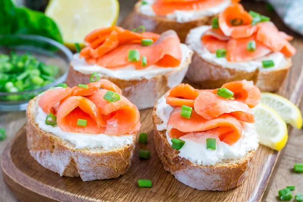 Сэндвич с копченым лососем и сливочным сыром на деревянной доске — стоковое фото