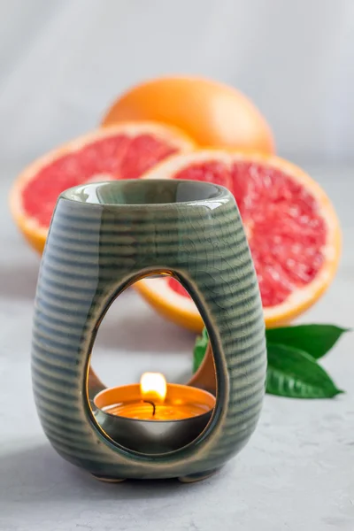 Aroma lampa s esenciální olej z grapefruitu, grapefruitů na pozadí — Stock fotografie